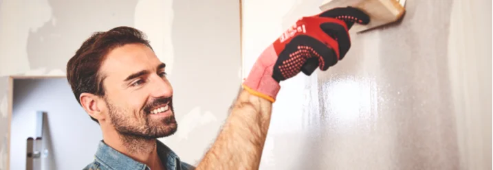 Person trägt mit Pinsel Grundierung auf Wand auf